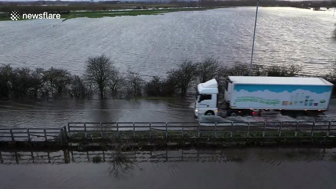 Vehicles plough through streets submerged by floodwater in northern UK