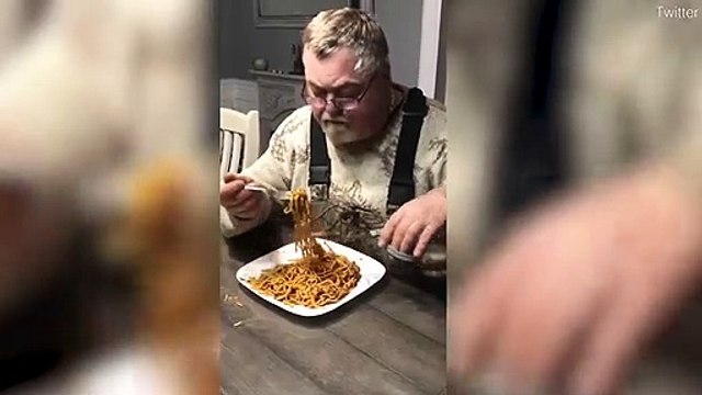 Un homme mange ses spaghettis en les découpant avec des ciseaux