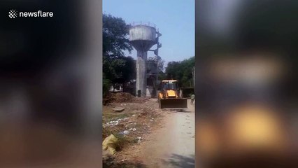 Bulldozer operator sent running when water tower collapses near his vehicle