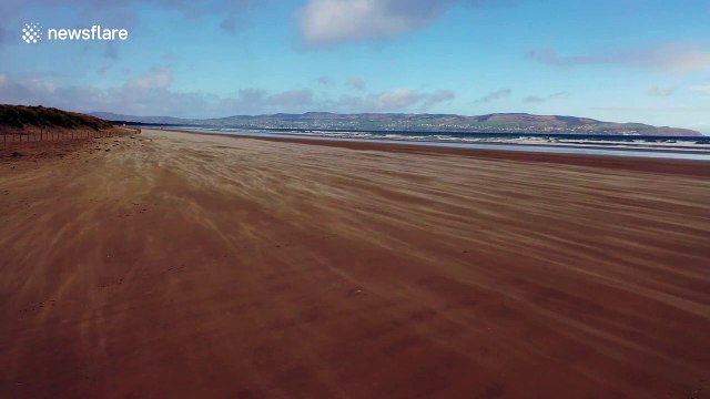 Dramatic drone footage captures gusts of wind blowing sand over UK beach