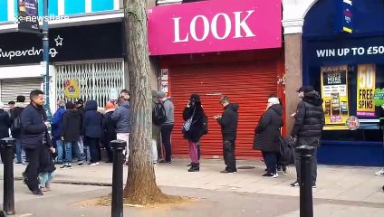 Customers queue outside London Superdrug for hand santiser