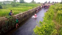 Indonesian kids use irrigation channel as water slide after heavy rain