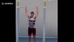 Six-month-old baby girl kicks legs while doing pull ups with super-fit dad