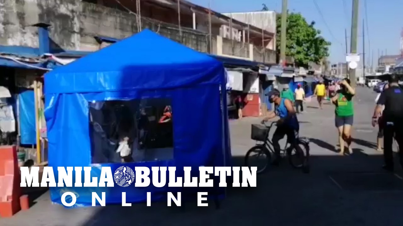Market goers enter disinfection tent upon enter...