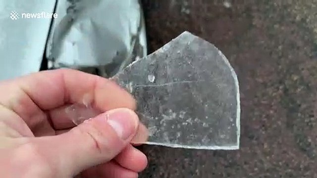 US driver has to kick incredibly thick layer of ice off his car