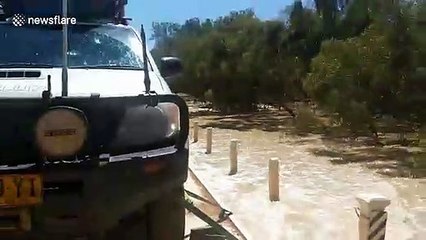 Vehicle drives through flooded roads after river overflows in western Queensland, Australia