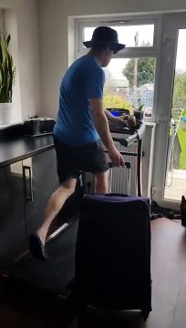 Durant le confinement, cet homme court avec sa valise sur son tapis de course.