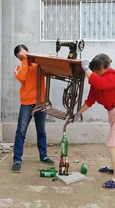 Ces deux Asiatiques réussissent à maintenir en équilibre une table de machine à coudre dont l’un des pieds est posé sur la tête d’une bouteille.