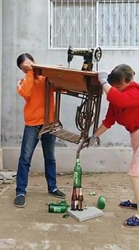 Ces deux Asiatiques réussissent à maintenir en équilibre une table de machine à coudre dont l’un des pieds est posé sur la tête d’une bouteille.
