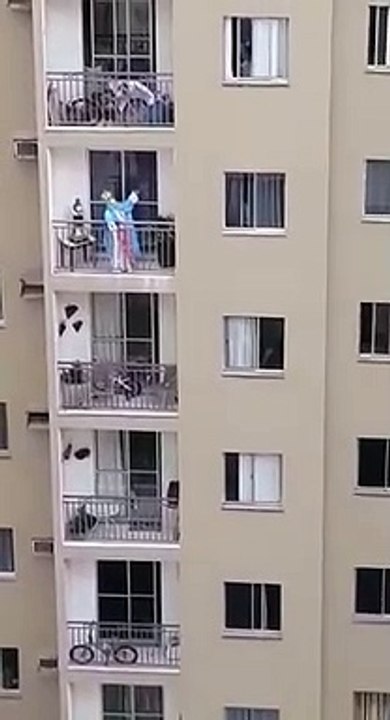 Mulher vestida de santa presta homenagem à Nossa Senhora da Penha da varanda de casa