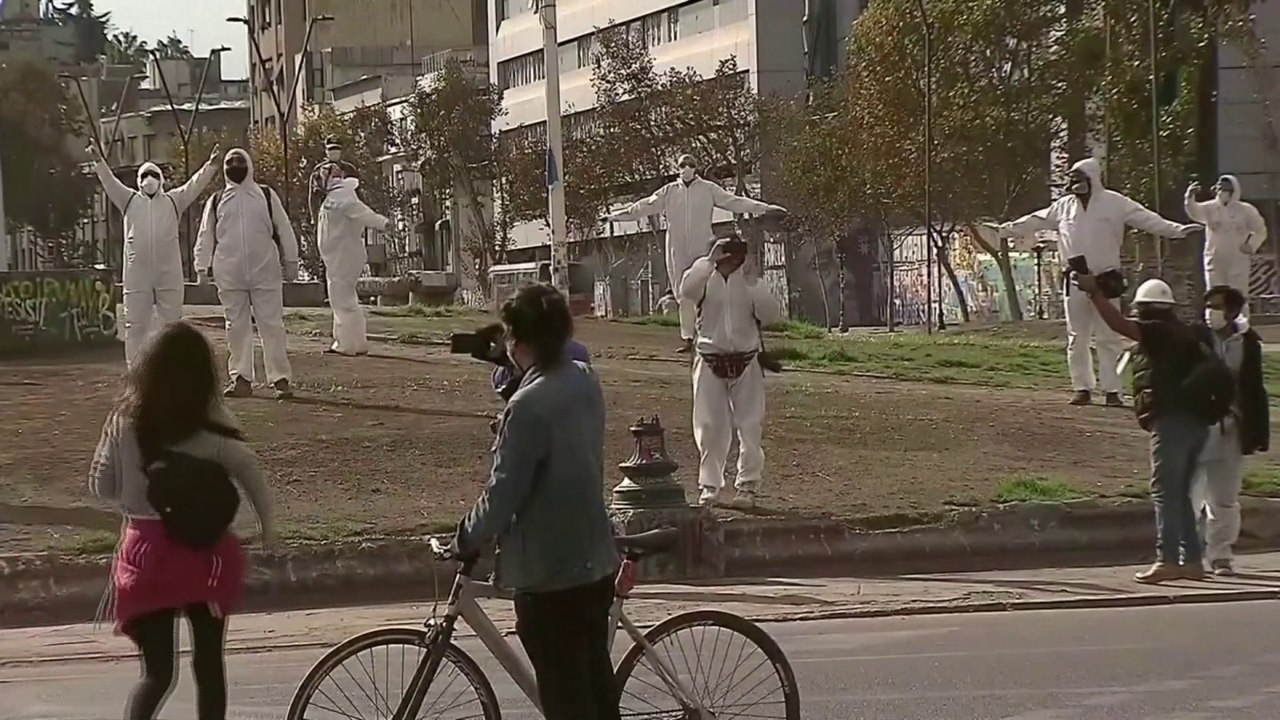 Masqués et en combinaisons de protection, des Chiliens manifestent pour dénoncer le report du référendum constitutionnel