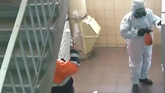 Deux employés font semblant de désinfecter un immeuble du coronavirus