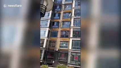Firefighters and police officers in China rescue child hanging out of third-floor window
