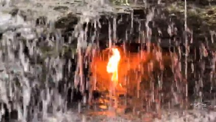 Eternal flame blazing behind waterfall