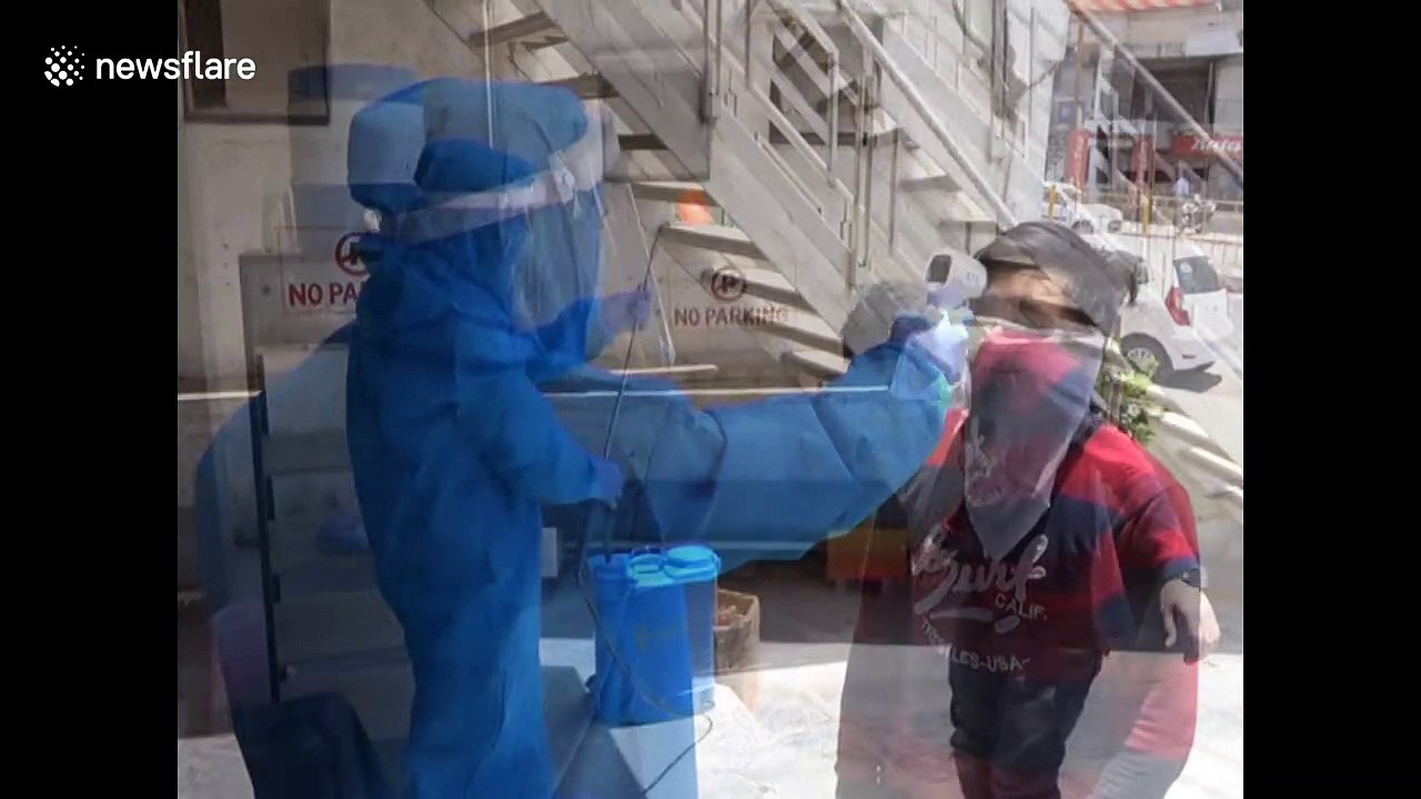 Barbers in western India wear protective gear while cutting hair