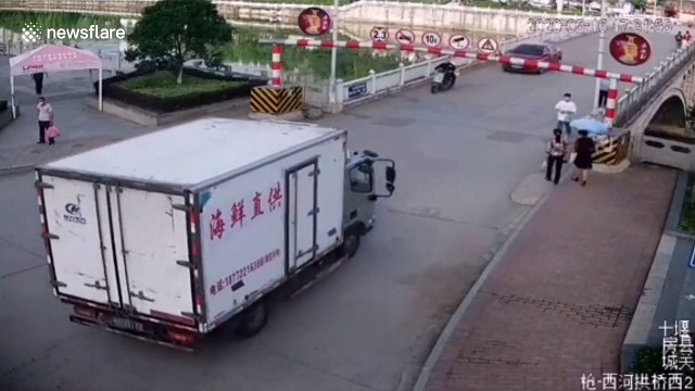 Chinese woman narrowly escapes being hit by height restriction barrier after truck knocks it down