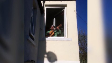 Man serenades wit his guitar from a window