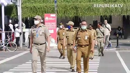 Penumpang menerapkan jarak sosial saat menaiki bus Transjakarta di Halte Harmoni, Jakarta.