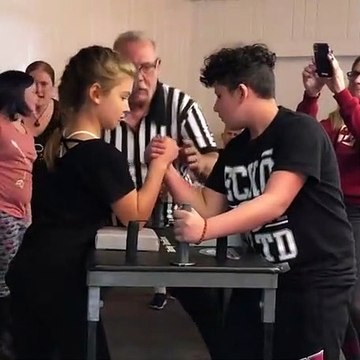 Une petite fille bat un garçon au bras de fer