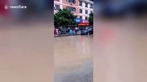 Chinese residents catch fish on flooded road after rainstorm