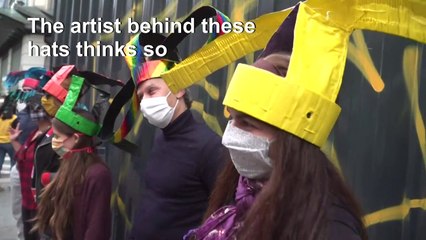 Artist's 'social distancing hats', with message, paraded in Paris