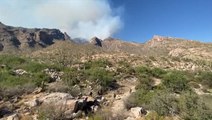 Firefighters clear brush as wildfire rages nearby