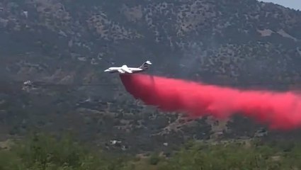 Plane drops fire retardant on mountainside