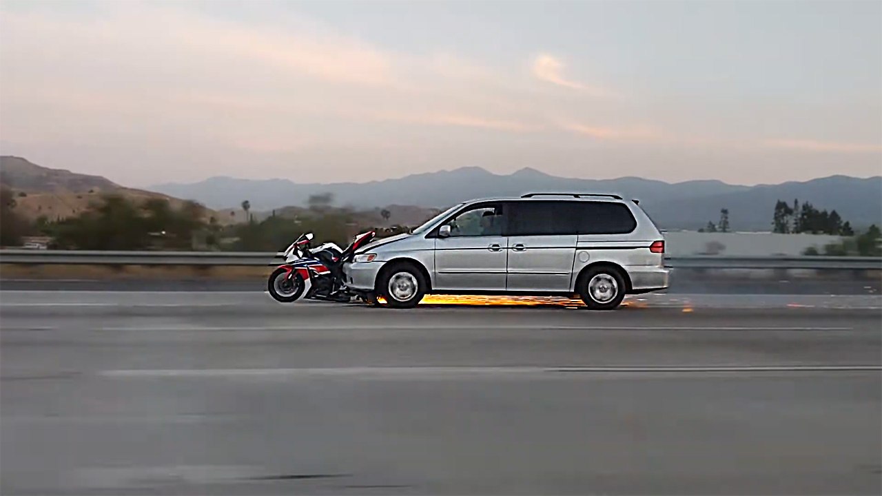 Une voiture roule en poussant une moto encastrée dans le par-chocs