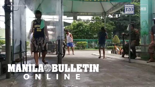 Residents pass through the disinfection booth before entering Barangay 23-C in Davao City