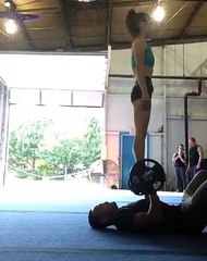 Il fait ses haltères avec une femme debout en équilibre sur la barre !