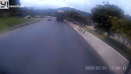 Motorcycle rider takes a short cut across road but is almost hit by oncoming lorry