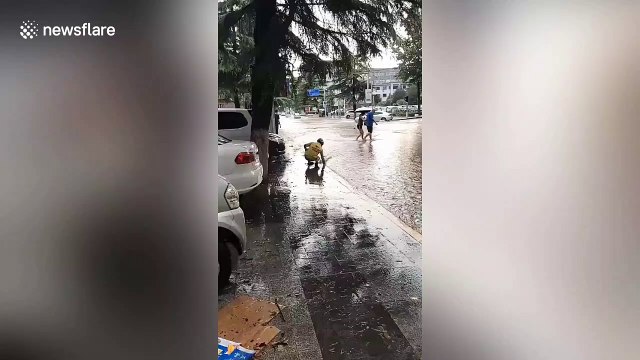 Deliveryman cleans street drains barehanded in China during heavy rain
