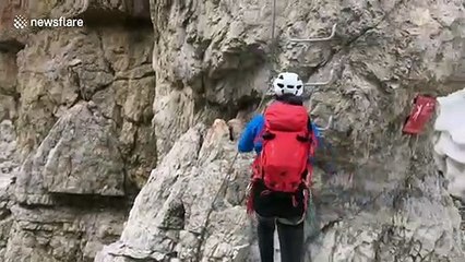 Mountaineers in the Dolomites scale cliff edge for breathtaking views