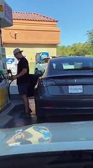 Cet homme cherche la trappe de réservoir sur sa Tesla