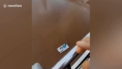 Man bemuses locals by drinking tea while floating on a plank in the Yangtze River