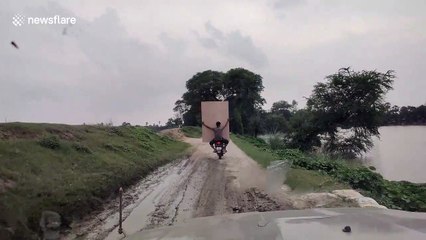 Do motorcycles and multitasking mix? For this man carrying plywood sheet, it sure does!