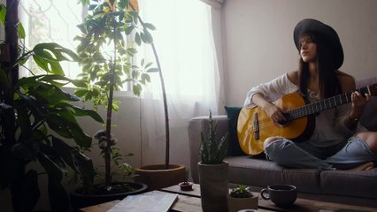 woman-playing-an-acoustic-guitar in her living room