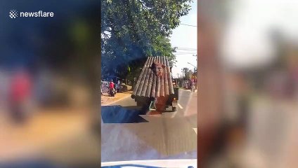 Reckless passenger clings onto metal pipes loaded onto back of truck