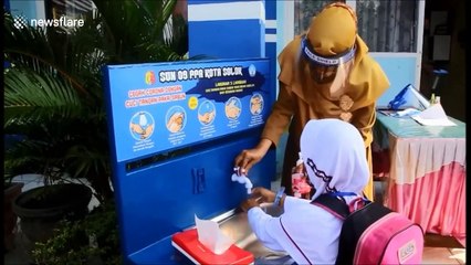 Schools in Indonesia reopen with children separated by plastic panels and wearing masks