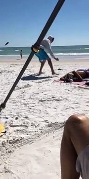 Un homme s’amuse à attirer les oiseaux sur une femme qui profitait du soleil et de la plage