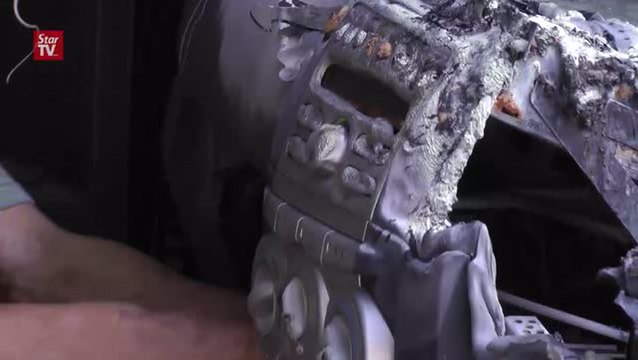 A burnt car is stripped of its damaged interiors