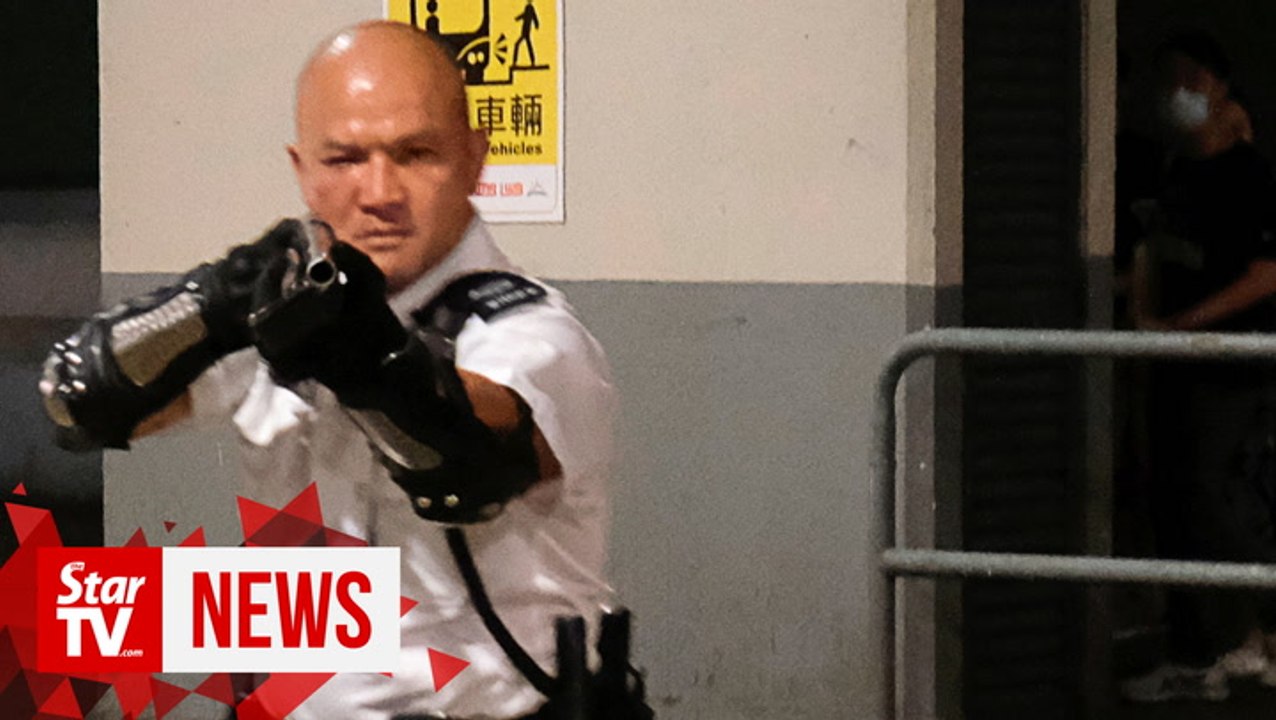 Police officer waves gun at Hong Kong protesters