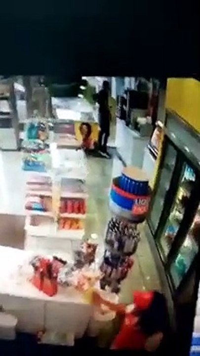 Hombre tira café recién servido a empleada de establecimiento de comida en estación de combustible Axion