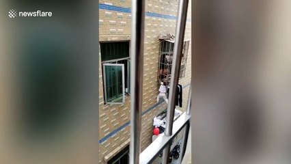 Chinese worker holds up toddler hanging from second-floor window until help arrives