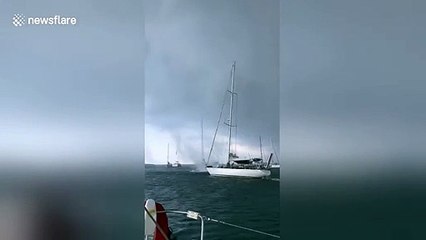Une trombe marine passe entre 2 bateaux en mer