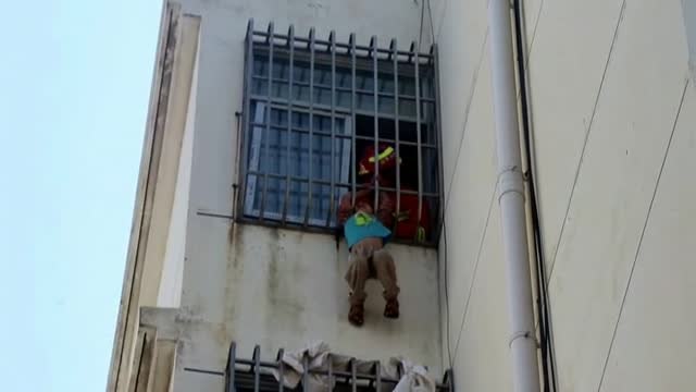 Angustioso rescate de los bomberos a un niño colgado en un quinto piso en China