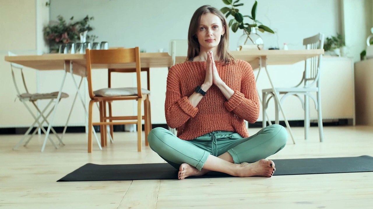 Beautiful woman in the field doing yoga with a smile.