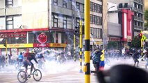 Protesters run as police fire rounds of tear gas during clashes in Bogota