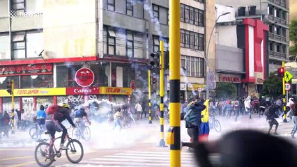 Protesters run as police fire rounds of tear gas during clashes in Bogota