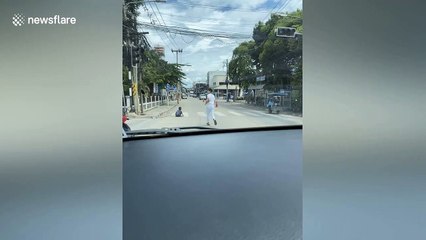 Kind motorist carries elderly disabled woman across the road in Thailand